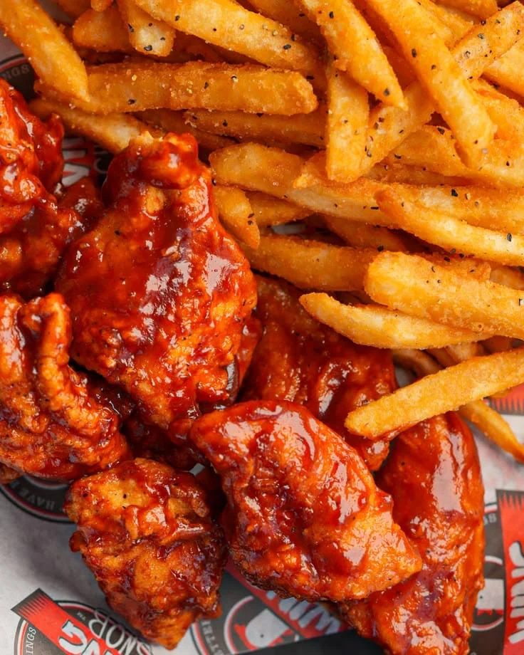 Alitas con salsa y papas fritas